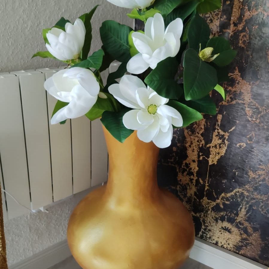 Blumen in goldener Vase Goldene Vase mit weißen Magnolienblüten und grünen Blättern.