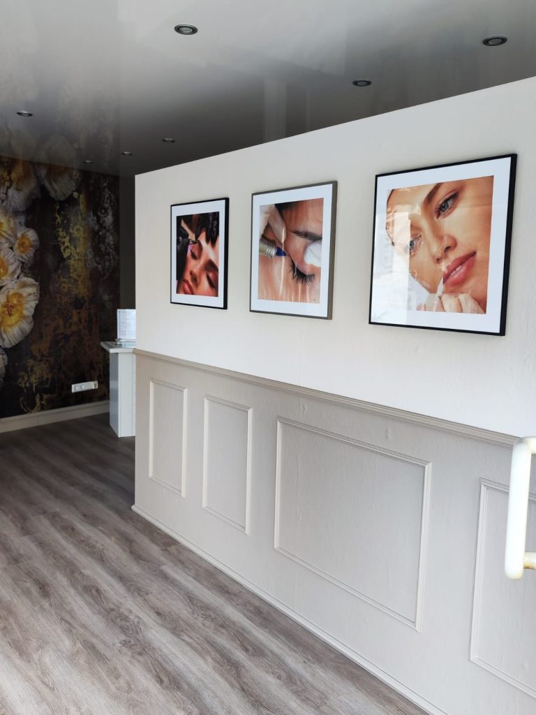 Wand mit Portraits Eine helle Wand mit drei gerahmten Portraits und einem modernen Empfangsbereich.