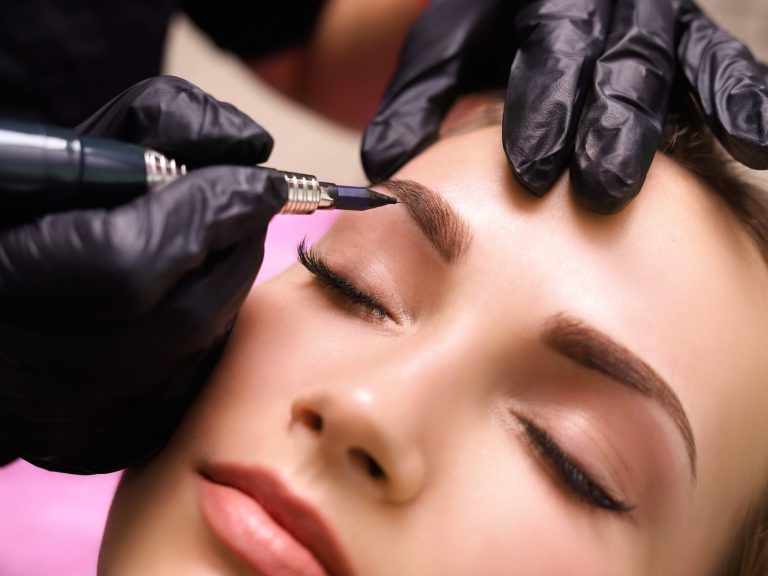 Wimpern Eine Person erhält ein Augenbrauen-Tattoo von einem Tätowierer mit Handschuhen.